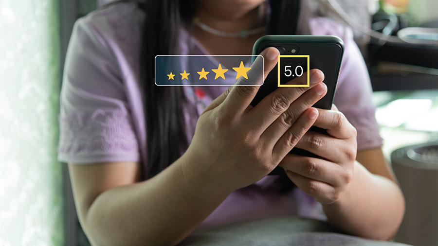 Person holding a smartphone showing a 5-star rating graphic with a 5.0 score overlay.